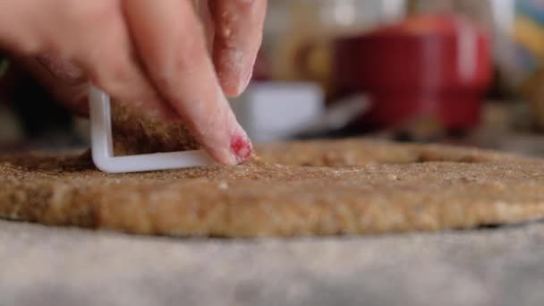 Frau schneidet Kekse auf Vollkornteig auf bemehlter Arbeitsplatte — Stockvideo