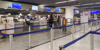 Frankfurt, Almanya, 12: 26 2019. Frankfurt Havaalanı 'nda iki farklı gişenin önünde duran genç adam ve kadın kayıt yaptırıyor ve bagajları kuyruk oluşturmadan bırakıyor. Verimli bir hizmet operasyonu.
