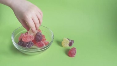 Childs hand takes marmalade from bowl,green backdrop.Easter treats for children