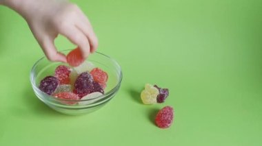 Çocuğun eli yeşil arka plandaki cam kaseden marmelatı alır, tatlı tavşancık, yumurta ve kelebek yalan söyler. Çocuklar için paskalya ziyafeti.