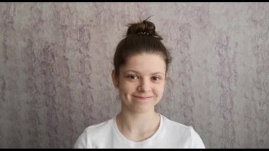 Saçlı bir kız kameraya bakıyor, gülümsüyor ve ellerini gösteriyor, Asyalı ya da Koreli bir kalp işareti yapıyor bu da demek oluyor ki seni iki eliyle çapraz seviyorum. K-pop hayranlarının jesti.