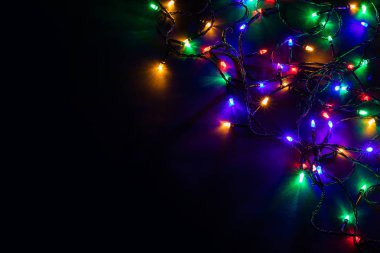 Işıklı ve bedava metin alanlı bir Noel arkaplanı. Noel ışıkları sınırda. Siyah arka planda parıldayan renkli Noel ışıkları. Yeni yıl. Noel zamanı. Dekorasyon. Çelenk.