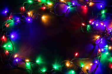 Işıklı ve bedava metin alanlı bir Noel arkaplanı. Noel ışıkları sınırda. Siyah arka planda parıldayan renkli Noel ışıkları. Yeni yıl. Noel zamanı. Dekorasyon. Çelenk.