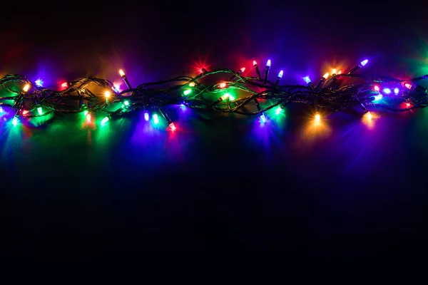 Sfondo natalizio con luci e spazio di testo libero. Luci di Natale confine. Luci di Natale colorate luminose su sfondo nero. Capodanno. Natale. Arredamento. Ghirlanda. — Foto Stock