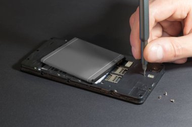 İnsan eli tornavida üstünde okul sırası ile cep telefonu tamiri