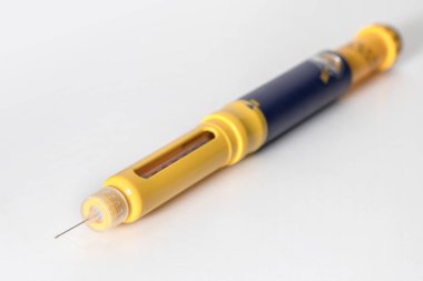 İnsülin kalemi, beyaz arka planda izole edilmiş iğne ucuyla insülin damlası. Tıbbi cihazlar, diyabet hastalığının kendine enjekte edilmesinde kullanılır. Dünya Diyabet Günü ve Sağlık Konsepti.