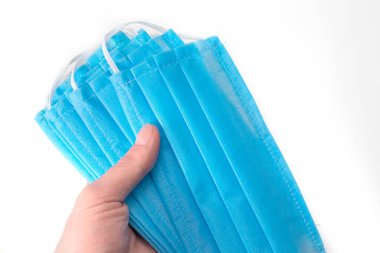 Beyaz arka planda el ele tutuşan tıbbi maske.