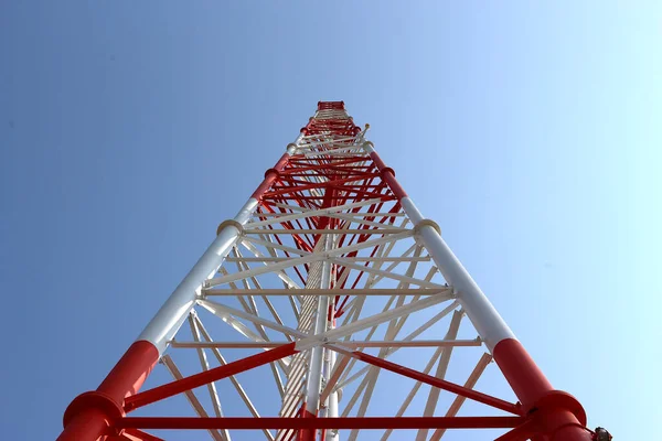 The telephone tower is white and red. View from bottom to top. Sky is background.