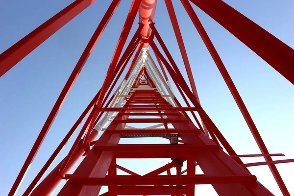 The telephone tower is white and red. View from bottom to top. Sky is background.