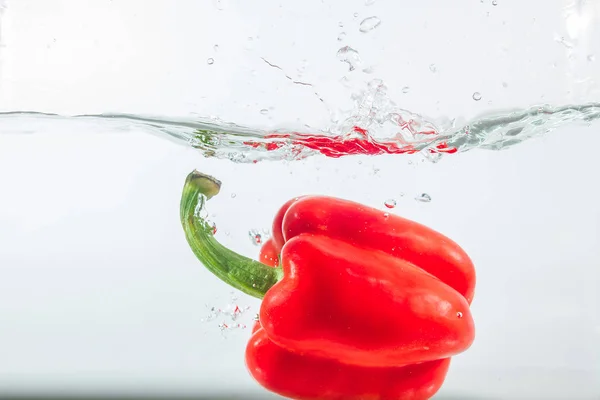 Sweet pepper in water splashes, red sweet pepper on a white background. Sweet peppers are a type of pepper. Not spicy