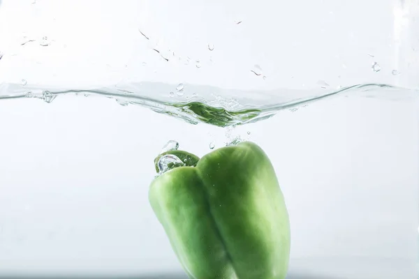 Sweet pepper in water splashes, green sweet pepper on a white background. Sweet peppers are a type of pepper. Not spicy