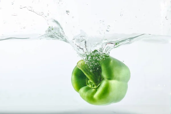 Sweet pepper in water splashes, green sweet pepper on a white background. Sweet peppers are a type of pepper. Not spicy