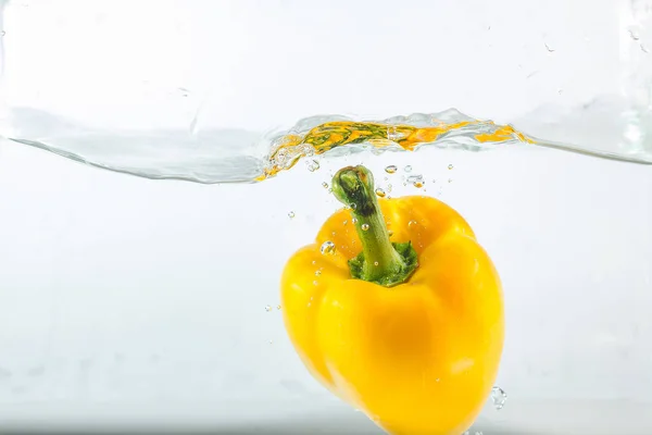 Sweet pepper in the water splashes, the yellow Sweet pepper on a white background. Sweet peppers are a type of pepper. Not spicy