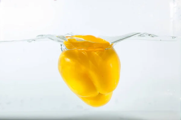 Sweet pepper in the water splashes, the yellow Sweet pepper on a white background. Sweet peppers are a type of pepper. Not spicy