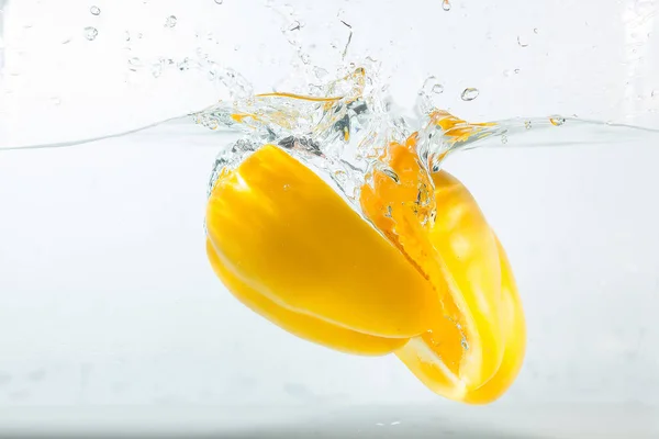Sweet pepper in the water splashes, the yellow Sweet pepper on a white background. Sweet peppers are a type of pepper. Not spicy