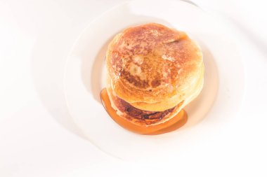 Krepler beyaz bir tabağa istiflenmiş, krepler balla kaplanmış.