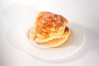 Krepler beyaz bir tabağa istiflenmiş, krepler balla kaplanmış.