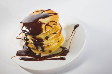 Beyaz bir tabağa istiflenmiş gözlemeler çikolatayla kaplıdır..