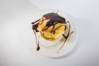 Beyaz bir tabağa istiflenmiş gözlemeler çikolatayla kaplıdır..