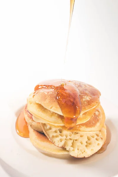 白いプレートに重ねられたパンケーキ パンケーキは蜂蜜でトッピングされています — ストック写真