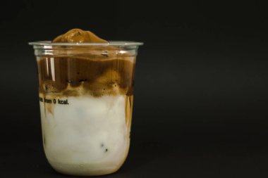 Plastik bardakta buzlu latte kahve. Siyah arka planda.