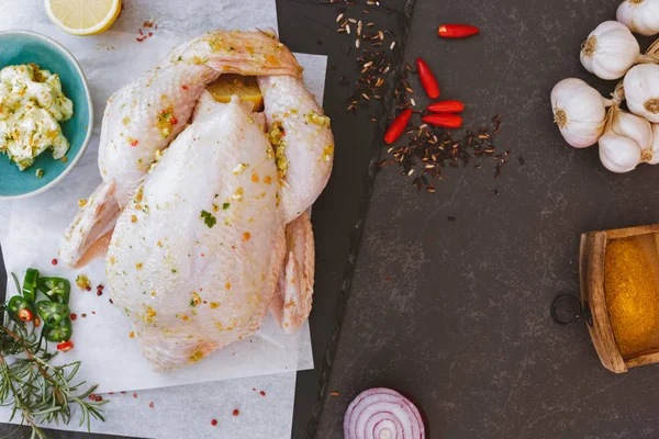 Pollo crudo entero sobre papel de hornear con condimento —  Fotos de Stock