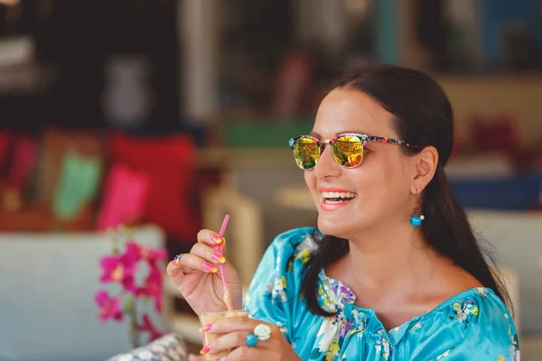 Elegante mujer con gafas de sol disfrutando de café helado en un café — Foto de Stock