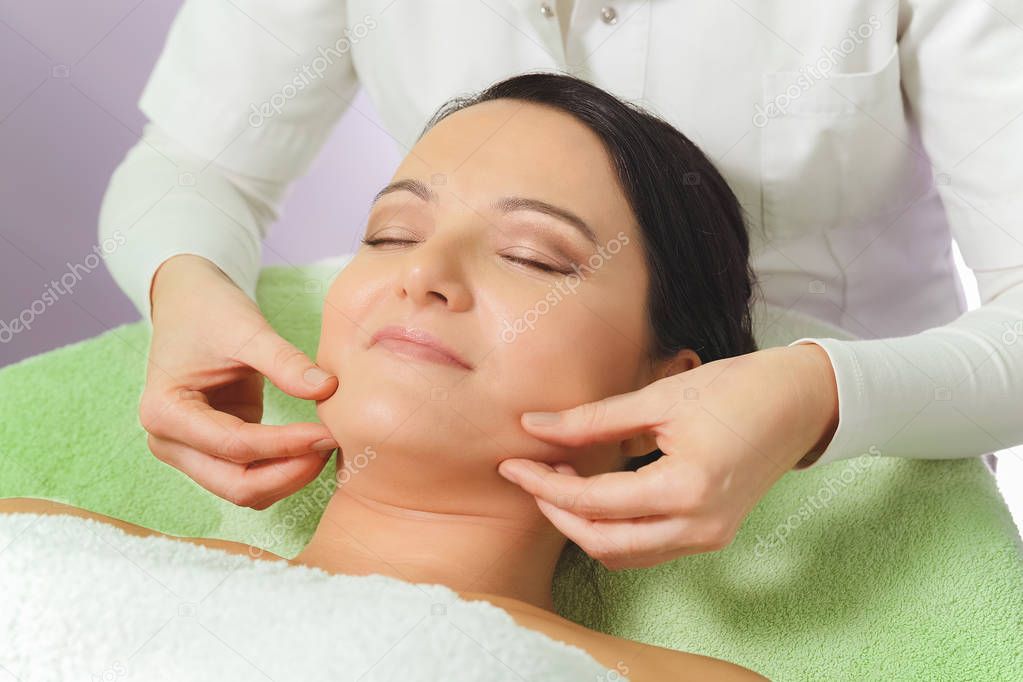 Woman enjoying a facial massage in spa