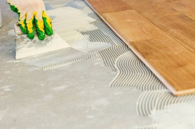 Usta, yapıştırıcıyı beton zemine sürüp parke serer, profesyonel parke serer..