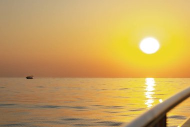 Balıkçıların siluetleri, parlak bir günbatımına karşı denizin altında büyük sarı bir güneş ile. Denizin üzerinde güzel bir gün batımı.