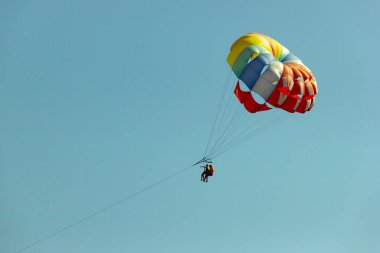 Mavi gökyüzüne karşı çok renkli paraşüt. Mutlu çift yazın Parasailing.