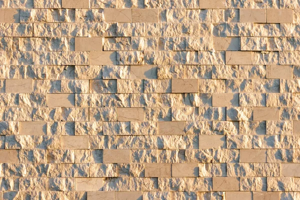 Textured marble tiles illuminated by the setting sun. Beige marble wall texture Wallpaper background.