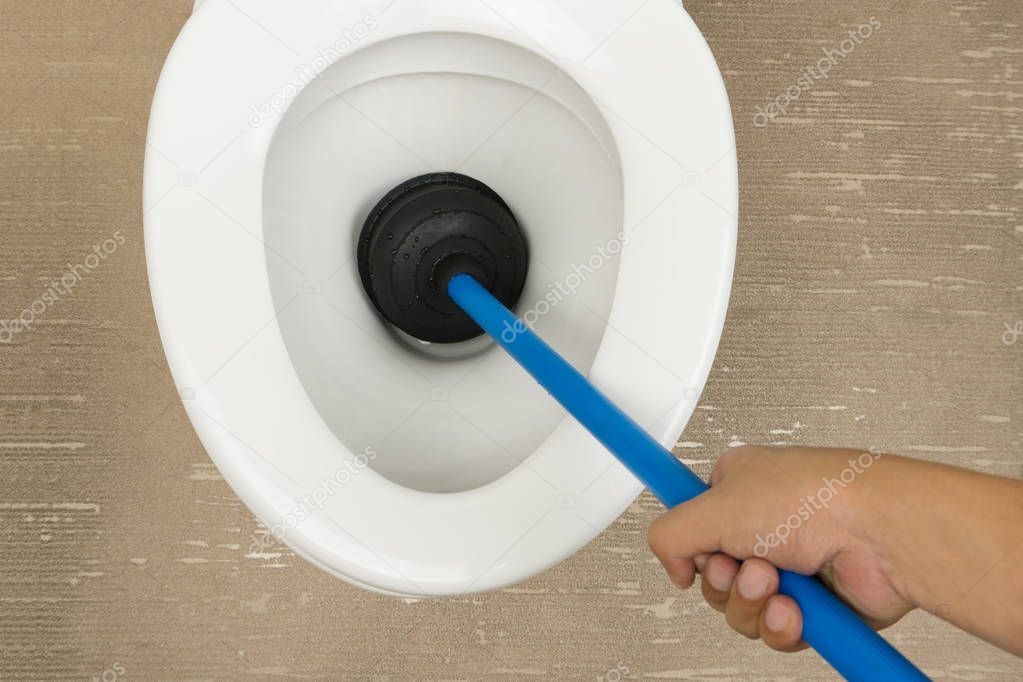 Plumber uses the rubber plunger to unclog the flush toilet