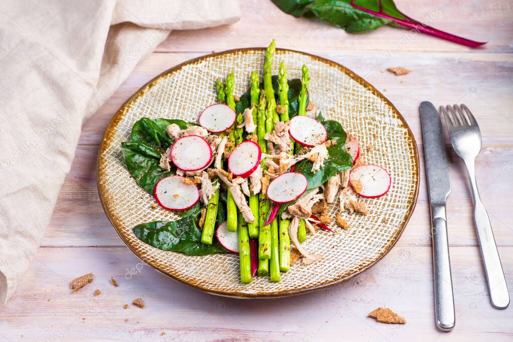 Asparagus salad with chicken, radish, beet leafs and rye crumb