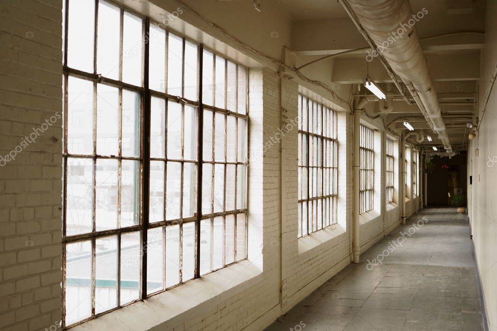 An empty industrial corridor with windows.