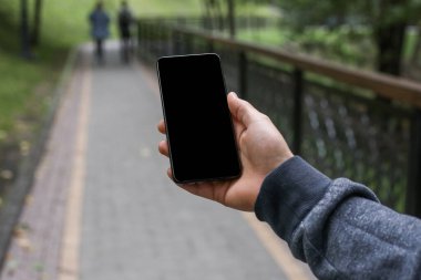 Model resim, insan yaşam tarzı GPS uydu navigasyon uygulamaları konsepti. Şehirdeki insanların bulanık geçmişine sahip mobil uygulama üzerinden mobil akıllı telefon arama konumu kullanılıyor