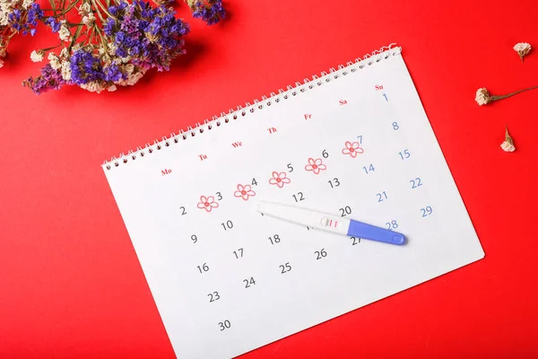 Périodes calendrier pour vérifier les jours de menstruation sur fond rouge. Médecine, santé, concept gynécologique. Test de grossesse positif avec date d'encerclement dans le calendrier. Planification de la grossesse, essayant de — Photo