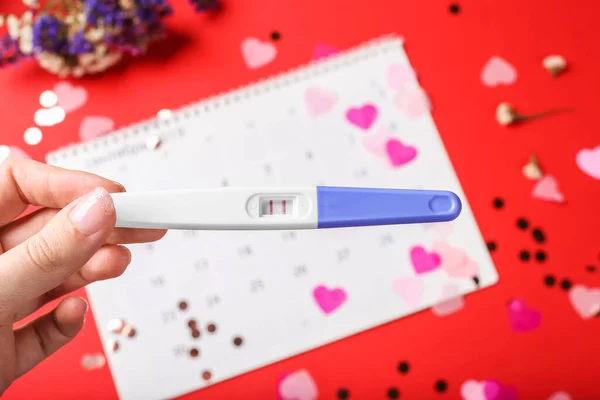 Test di gravidanza positivo nella donna mano su sfondo calendario periodo — Foto Stock