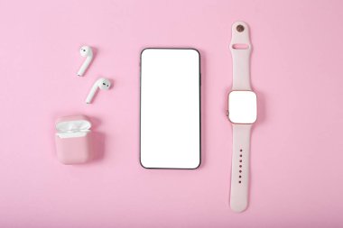 Pembe arka planda akıllı kadın zımbırtıları var. Kulaklıklar, akıllı saat ve akıllı telefon. Fotokopi alanı olan üst görünüm, düz. Kadın aygıtları modeli