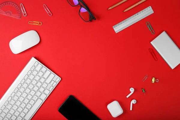 Mockup of smart gadgets on the background of office items on red background. Computer mouse and keyboard, headphones, office tools and powerbank. Top view with copy space, flat lay. Woman devices
