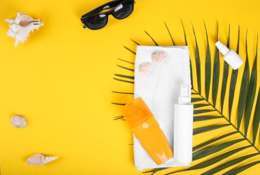 Plaj düz aksesuarları ve fotokopi alanı. Deniz kabukları ve sarı arka planda bir şişe güneş kremi. Yaz tatili konsepti. Seyahat kavramı