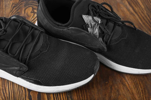 black torn sneakers dirty on wood background, Footwear for outdoor activities. Torn shoes. Shoe repair.