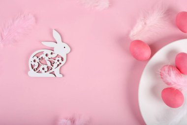 Mutlu Paskalyalar. Paskalya arkaplanını tebrik ederim. Paskalya yumurtaları ve pembe tüylerle süslenmiş Paskalya tavşanı. Moda konsepti. Üst görünüm, düz görünüm, model