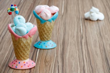 mavi ve pembe kremalı kekler ahşap arka plan ve beyaz meringues pembe ve mavi koni içinde