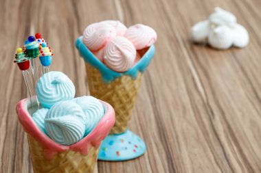 mavi ve pembe kremalı kekler ahşap arka plan ve beyaz meringues pembe ve mavi koni içinde