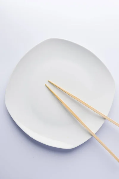 하얀 배경에 놓인 접시에 젓가락을 얹는 모습 — 스톡 사진