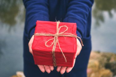 Bir kırmızı bir kutu hediye ormanda, kış günü tutan kadın