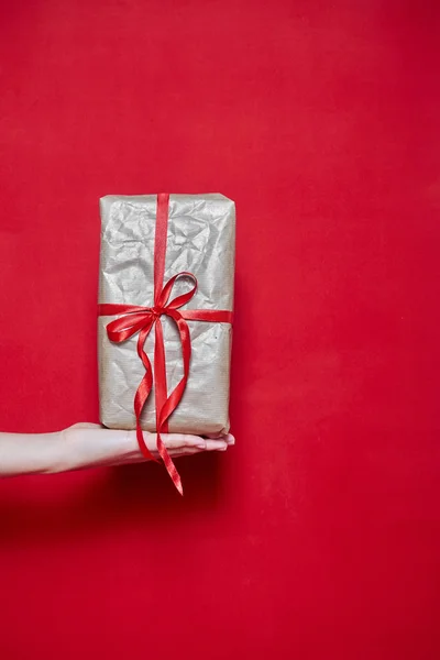 Womans Hand sosteniendo un regalo de caja sobre fondo rojo —  Fotos de Stock