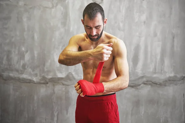 El hombre está envolviendo las manos con envolturas rojas de boxeo . — Foto de Stock