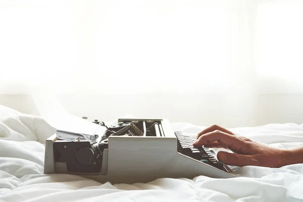 Χέρια ανδρών πληκτρολογώντας σε vintage γραφομηχανή στο κρεβάτι — Φωτογραφία Αρχείου